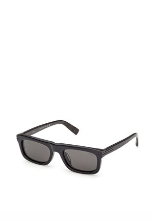 Černé obdélníkové sluneční brýle s tmavě tónovanými čočkami a elegantními rameny, zobrazené na bílém pozadí.