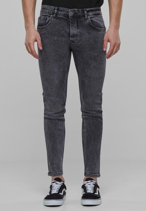 Zesvětlené černé džíny skinny s hladkou texturou, designem s pěti kapsami, zapínáním na knoflík a jemným omíláním na stehnech.