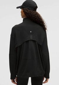 Čierny pulóver s vysokým golierom a vrstveným designom na chrbte. Mäkká tkanina, voľný strih a malé logo na strednej časti chrbta. Dlhé rukávy.