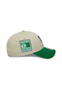 Beige Kappe mit grünem Schirm, ausgestattet mit dem "BOSTON CELTICS"-Logo und dem Text "EST. 1946" in grün und weiß, mit bestickten Akzenten.