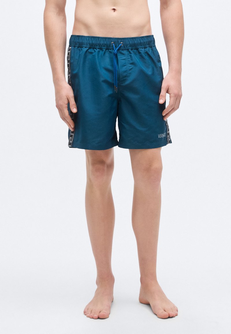 Τιρκουάζ μαγιό σορτς από ελαφρύ ύφασμα, με ελαστική μέση και μπλε κορδόνι, διακοσμημένο με μοτίβο στα πλάγια.