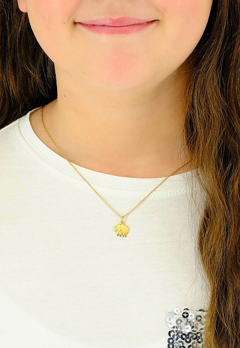 Collier pendentif éléphant en or sur une chaîne fine, porté sur une chemise blanche. Le pendentif présente des formes simples et arrondies ainsi que des détails.