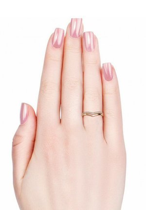 Goldfarbener Chevron-Ring, verziert mit kleinen klaren Steinen, an einer Hand mit langen, hellrosa, quadratisch geformten, gepflegten Nägeln. Der Hautton ist hell.