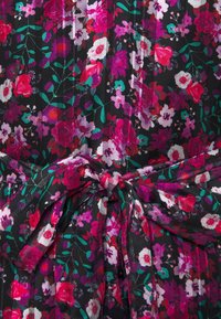 Kukallinen mekko, jossa on musta tausta ja värikkäitä vaaleanpunaisia, punaisia ja violetteja kukkia. Sisältää sidotun vyötarenkaan ja laskostetun tekstuurin.