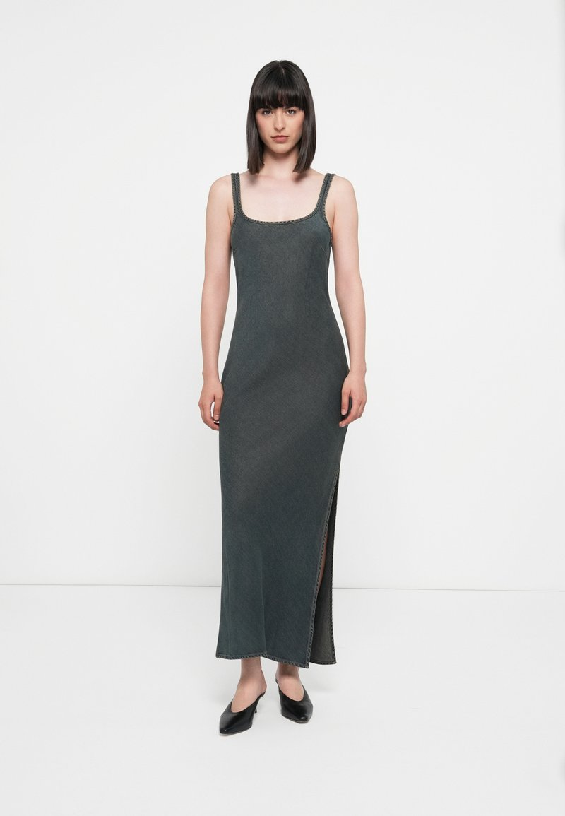 Sleeveless maxi dress in dark grey, featuring a square neckline, side slit, and decorative stitching along the straps and hem.