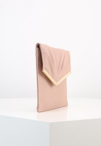 Rosa strukturierte Clutch mit einem gefalteten Klappendesign, ausgestattet mit einem goldfarbenen Metallelement und glatten Kanten, vor einem weißen Hintergrund.