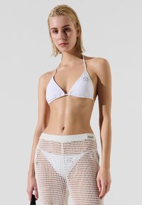 White bikini top with triangular cups, and matching white netted pants with a wide waistband. Smooth fabric and open mesh texture.