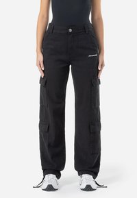 Black cargo pants feature multiple side pockets, a relaxed fit, and a button closure. "PEGADOR" logo is visible on the front.