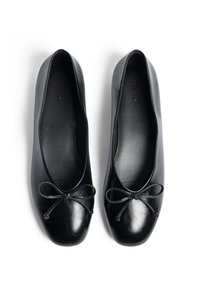 Bailarinas negras hechas de cuero liso, con puntas redondeadas y un lazo decorativo en la parte delantera. Diseño sencillo y elegante con acentos mínimos.