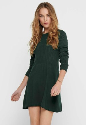 Robe en tricot côtelé vert foncé avec des manches longues et une jupe évasée. Texture douce, col rond et corsage ajusté se transformant en jupe.