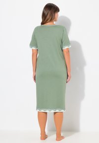 Camicetta da notte verde in cotone con maniche corte, caratterizzata da un bordo in pizzo sulle maniche e sull'orlo. Design lungo fino al ginocchio, dalla vestibilità ampia.
