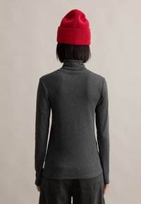 Grå langermet turtleneck med en tettsittende design og glatt tekstur, kombinert med en rød strikket lue. Bakperspektivet viser minimal detaljering.