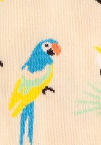 Colorful parrot knitting pattern with blue, yellow, green, and orange details on cream fabric background.