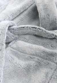 Lichtgrijze, zachte nep bontdeken met een fluweelachtige textuur, met een glad, gelijkmatig oppervlak en licht golvende plooien. Geen patronen of accenten.