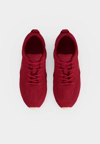 Paire de baskets de sport rouges à lacets avec languette de marque et détails texturés, vues de dessus sur fond blanc.