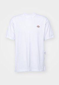 T-shirt blanc à manches courtes et col rond avec un petit logo Dickies rouge, bleu et orange sur la poitrine gauche, présenté sur un fond uni.
