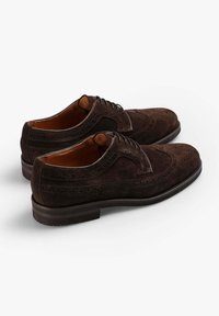 Zapatos oxford de ante marrón con detalles brogue, plantillas de cuero y suela de goma. Presentan una puntera redondeada y un sistema de cordones.