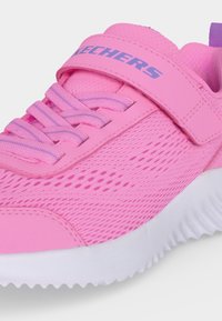 Baskets Skechers roses avec tissu en mesh, lacets violet clair, une bride velcro et une semelle blanche rainurée.
