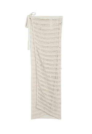 Fustă lungă bej, croșetată cu model deschis, cu design înfășurat și cu cordoane atașate în talie, prezentată întinsă pe un fundal alb.