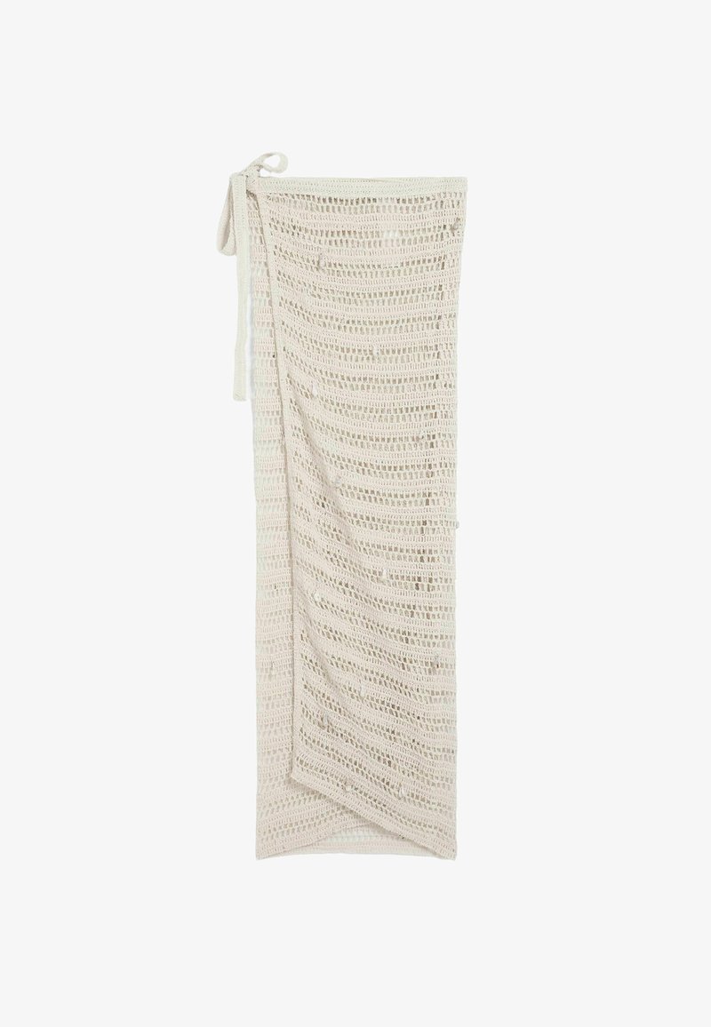 Longue jupe beige en crochet à mailles ouvertes avec design portefeuille et liens de taille attachés, présentée à plat sur un fond blanc.