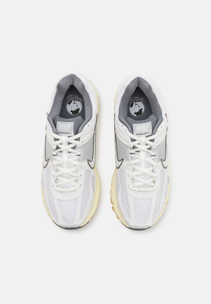 Witte mesh hardloopschoenen met grijze en zilveren accenten, voorzien van een patroonzool, een ronde neus en veters. Nike-logo op de tong.