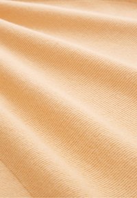 Jasnopomarańczowa tkanina o fakturowanej, prążkowanej powierzchni, ukazująca miękkie fałdy i gładkie krzywizny w różnych odcieniach pomarańczy.