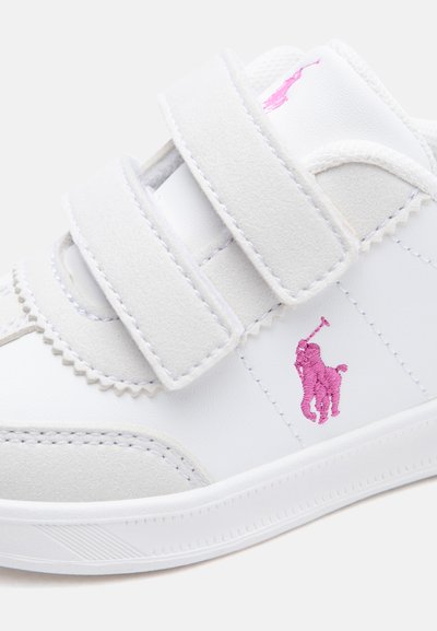 Zapatilla blanca con dos correas de velcro y un logo bordado rosa de un jugador de polo en el lateral.