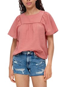 Rosa Leinenbluse mit kurzen Ärmeln, versehen mit Paspel-Details und einem lockeren Schnitt, kombiniert mit ausgewaschenen Denim-Shorts.