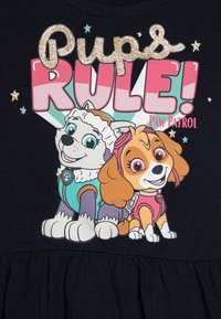 Paw Patrol majica s grafikom koja prikazuje dva crtana psa. Dizajn uključuje sjajni natpis "Pseći vladari!" na tamnoplavoj pozadini.
