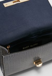 Šedá kabelka z umělé krokodýlí kůže se zlatými doplňky a námořnickým saténovým interiérem. Obsahuje zipovou kapsu a štítek River Island uvnitř.