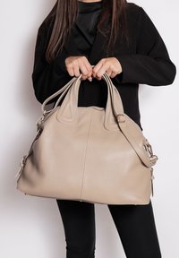 Borsa a mano in pelle beige con texture, dotata di doppi manici e una tracolla regolabile; presenta una chiusura a zip e dettagli in metallo sui lati.