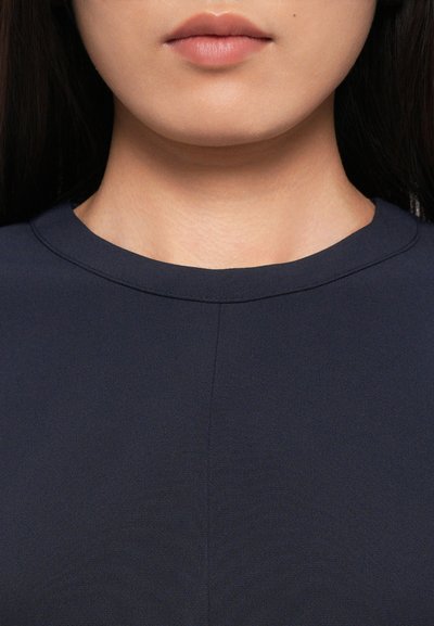 Navy blue garment with a round neckline, smooth texture, and subtle seam detail at the center, framing the collarbone area.