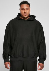 Sort ribbet hoodie med en forlommes, lange ærmer og en bred hætte. Lavet af blødt, tekstureret stof med en afslappet pasform.