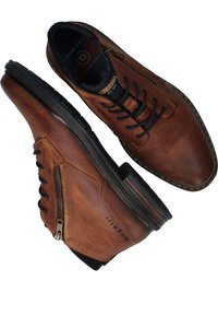 Chaussures en cuir marron avec une finition texturée, dotées d'une fermeture éclair sur le côté et d'un système de laçage, complétées par une semelle en caoutchouc noir.