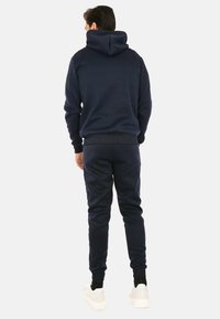 Felpa con cappuccio blu navy e pantaloni della tuta in materiale fleece, dotati di cappuccio con coulisse, polsini a costine e design aderente.
