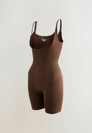Bodysuit modelant brun avec bretelles ajustables, design sans couture, texture côtelée et jambes courtes, mettant en valeur une silhouette lisse.