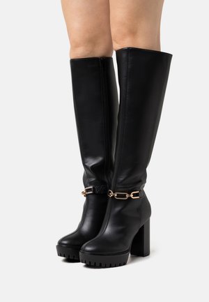 Bottes noires hauteur genou en cuir lisse, dotées d’un talon épais, d’accessoires dorés, d’une boucle à l’avant et de semelles crantées.