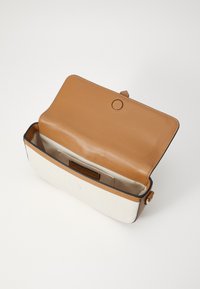Tan leather and cream canvas handbag with a flap closure, featuring a smooth interior and a front pocket label. Dimensions not specified.