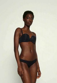 Black undergarment set featuring a padded, seamless push-up bra with thin straps and matching low-rise bikini briefs. Smooth texture.