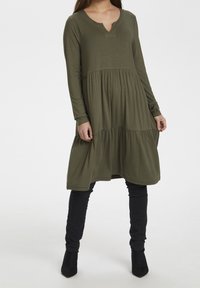 Oliwkowa sukienka z długim rękawem i dekoltem w kształcie litery V, z warstwowym dołem. Wykonana z miękkiego materiału, posiadająca swobodny krój i delikatną fakturę.