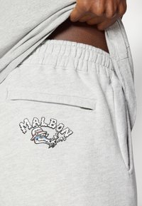 Ανοιχτό γκρι βαμβακερές φόρμες με ελαστική μέση, μια τσέπη και ένα γραφικό λογότυπο που περιέχει το κείμενο "MALBIM" και ένα καρτουνίστικο σχέδιο ψαριού.