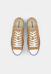 Bruine canvas sneakers met witte veters, rubberen neuzen en zwarte zool. Voorzien van een gewatteerde kraag en merk op de binnenzool.