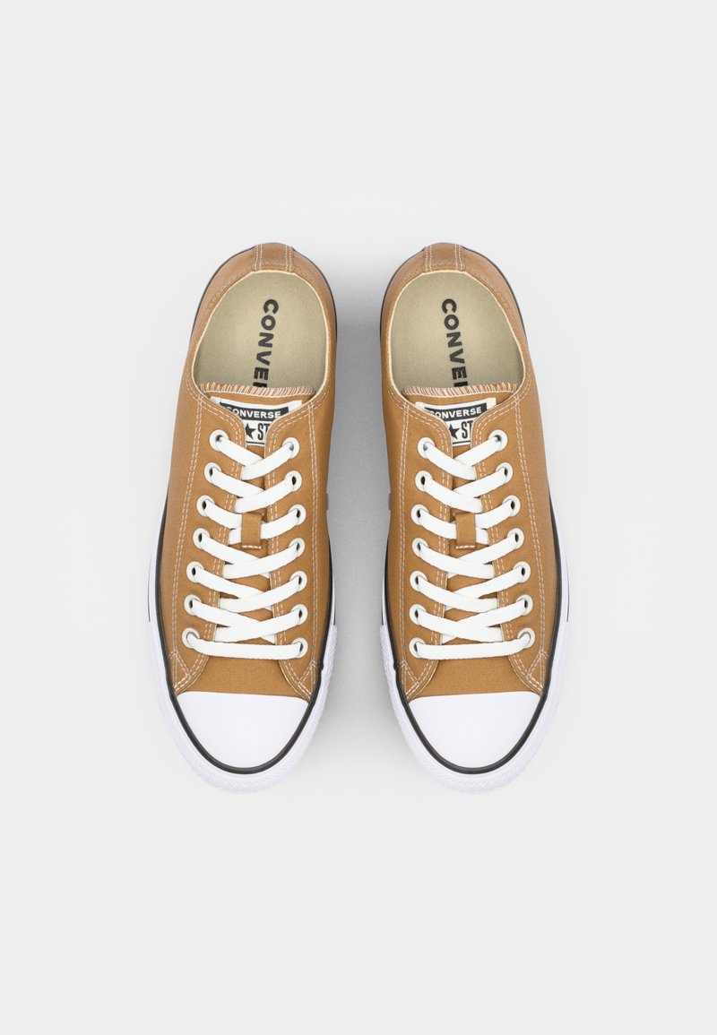 Zapatillas de lona marrones con cordones blancos, punta de goma y suela negra. Presentan un collar acolchado y branding en la plantilla.
