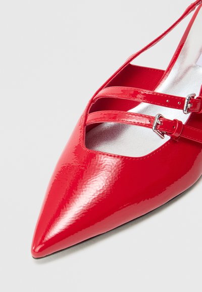 Red pointed-toe shoe with a glossy patent finish, featuring two ankle straps with silver buckles and a metallic silver insole.