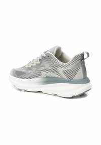 Zapatilla atlética gris con parte superior texturizada, suela de amortiguación blanca y acentos en azul claro. Presenta cordones y una pestaña de agarre en el talón.
