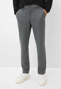 Pantalon gris ajusté en tissu texturé avec une taille boutonnée, des poches latérales et une coupe slim, associé à des baskets blanches.
