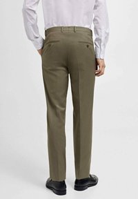 Olivgrüne, taillierte Hose mit geradem Schnitt, zwei Gesäßtaschen und glatter Textur. Mit braunen Knöpfen zum Schließen der Taschen.