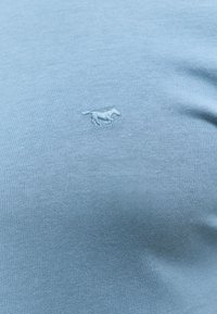 Jasnoniebieska bawełniana koszulka z małym haftowanym logo konia. Tkanina ma gładką fakturę i dopasowany krój.