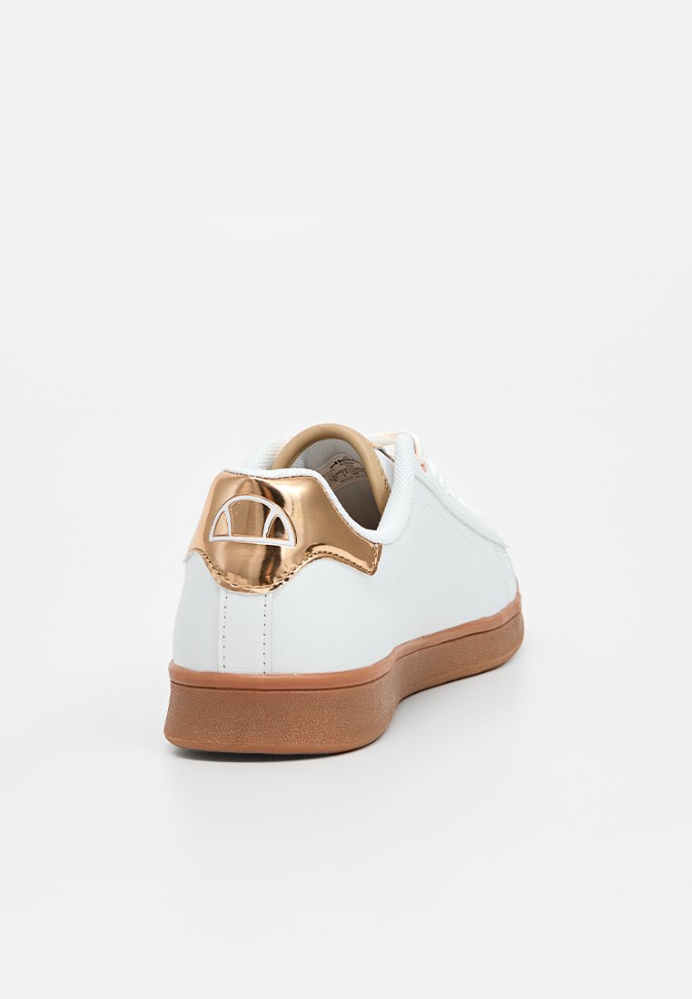 Zapatilla blanca con parte superior de cuero liso, suela de goma marrón y un acento metálico dorado en el talón que presenta un diseño de logo circular.