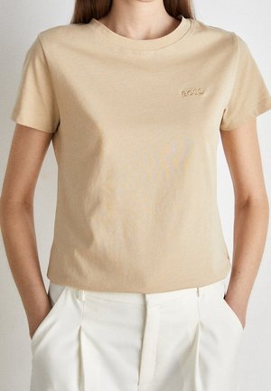 Beige bomulds t-shirt med rund hals, korte ærmer og et lille prægede "BOSS" logo på venstre bryst. Glat tekstur, afslappet pasform.